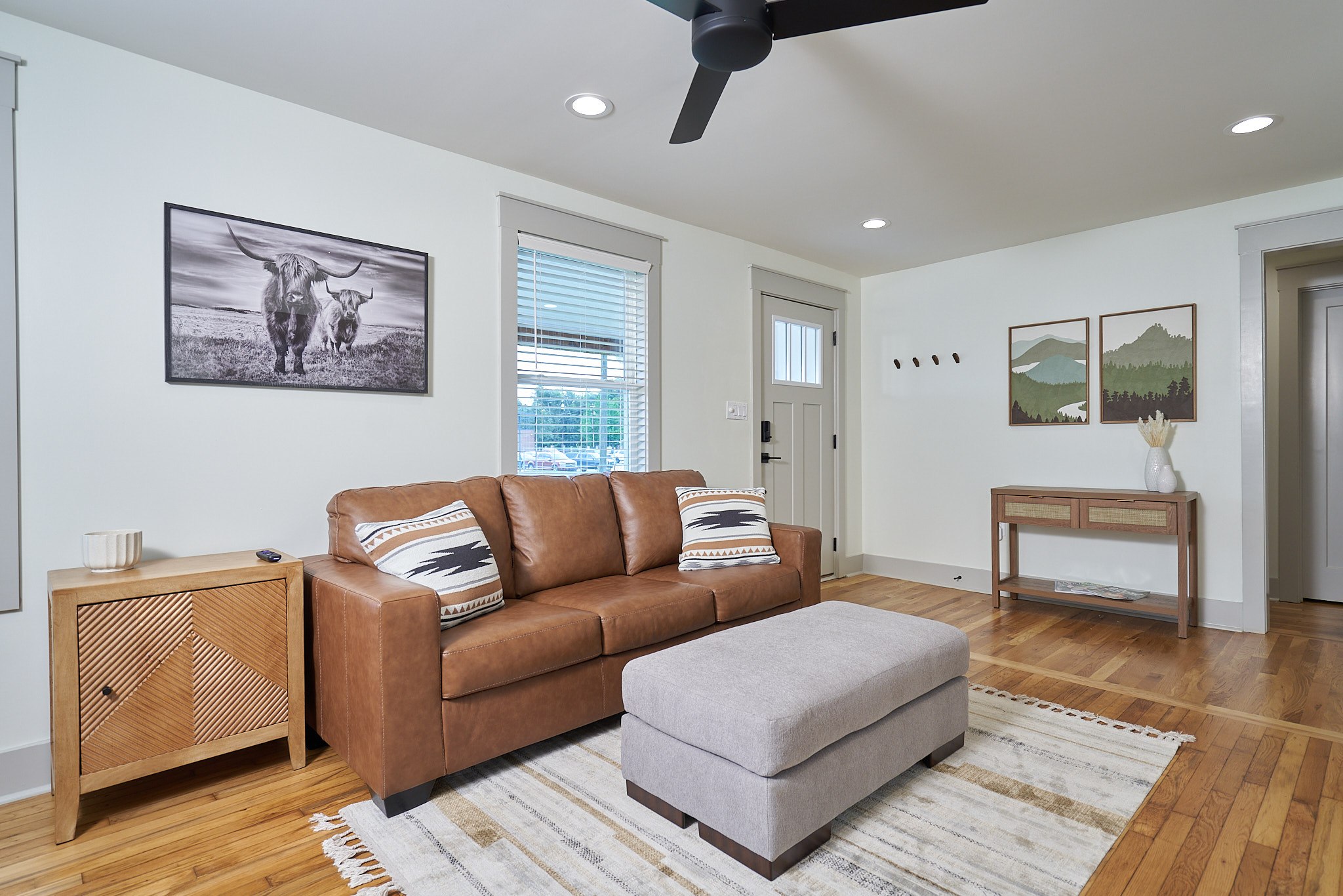 Reconfigured living room with a leather sofa, relocated front door, and refinished hardwood floors
