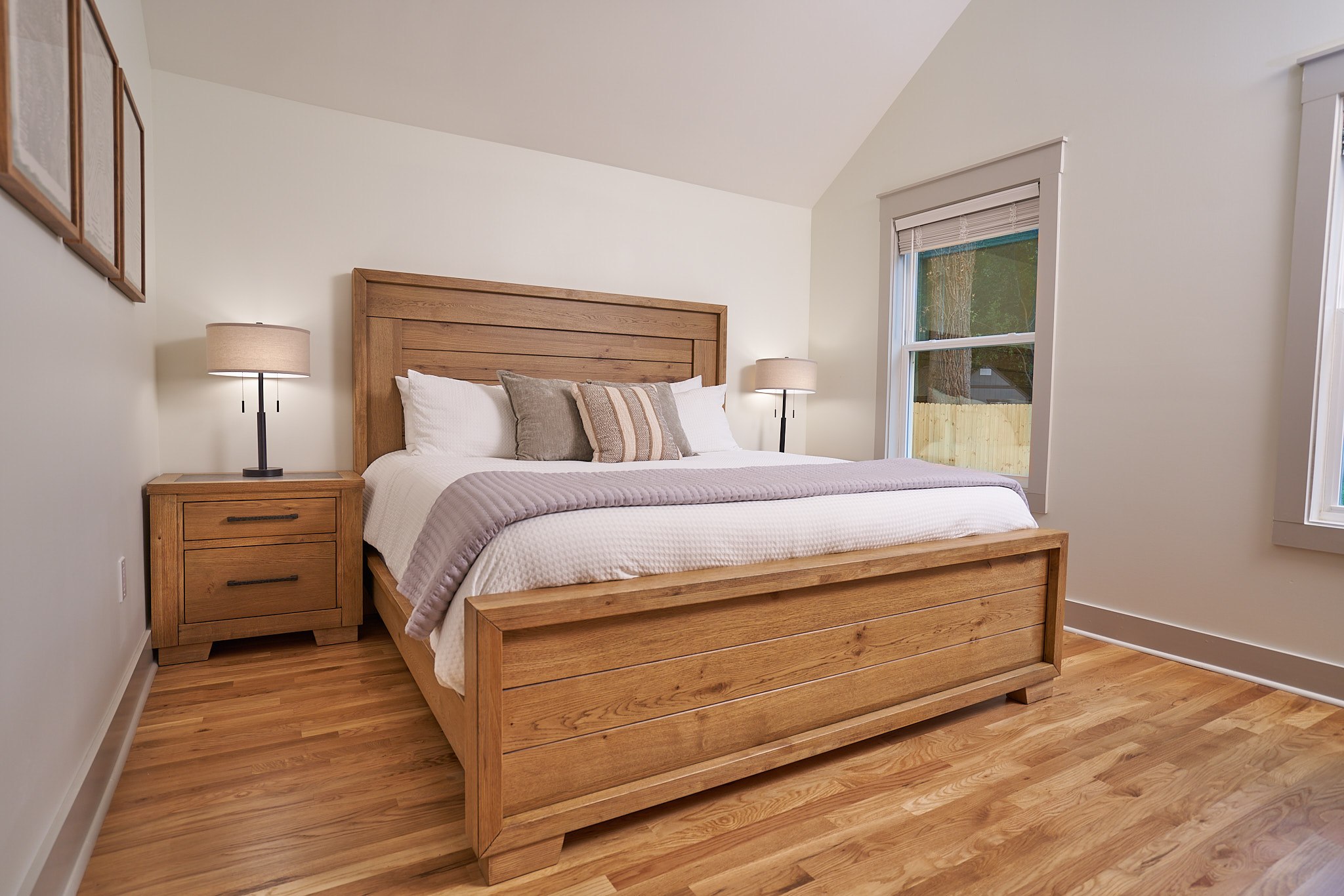 Master bedroom with vaulted ceilings, wood furniture, and refinished hardwood flooring